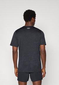 Zwart sport T-shirt met een subtiel camouflagepatroon, ronde hals, korte mouwen en een merklogo op de bovenrug.
