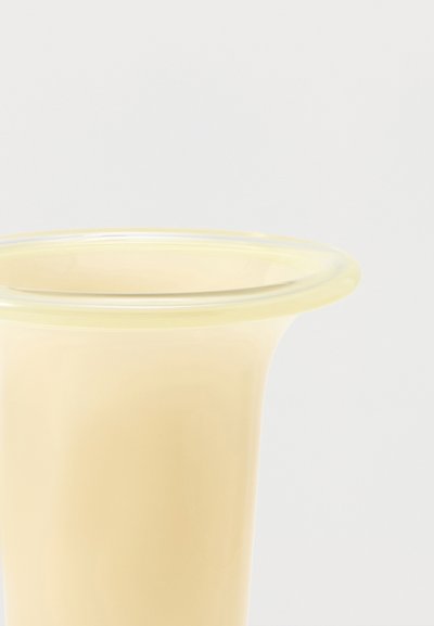 Κοντινή λήψη του πάνω μέρους ενός διαφανούς, ανοιχτόκίτρινου πλαστικού ή σιλικόνης χωνιού σε απλό φόντο.