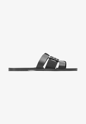 Sort slid sandal med en glat syntetisk overdel, brede stropper og en flad sål. Minimalistisk design med kontrasterende accenter.