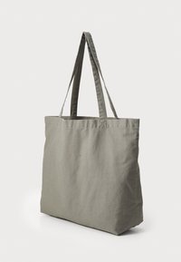 Borsa a tracolla in cotone grigia con due lunghe maniglie, forma rettangolare e design minimalista. Texture morbida e senza hardware o decorazioni visibili.