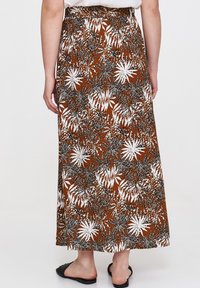 Brąskowa sukienka maxi z kwiatowym wzorem, ozdobiona białymi i czarnymi liśćmi, z paskiem w talii oraz gładkiego materiału. Zaprojektowana dla wygodnego dopasowania.