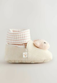 Chausson de couleur crème en tissu texturé avec un revers rayé rose et blanc. Décoré d'un détail de visage d'ours en peluche sur le côté.
