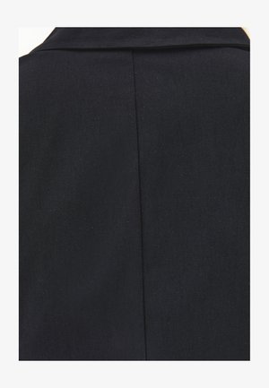 Gros plan du col arrière et de la couture centrale d'une veste formelle noire en tissu lisse légèrement texturé.