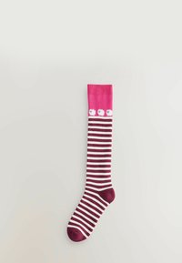 Knästrumpa med rosa överdel och vita ränder, med tre vita pom-pom detaljer. Materialet ser mjukt och elastiskt ut.