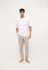 Tricou alb din bumbac cu logo-ul "TOMMY HILFIGER", asociat cu pantaloni de trening gri deschis, cu o croială îngustă și manșete elastice.