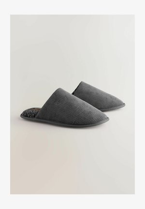 Harmaat liukujalkineet, joissa on tekstuuri päällinen ja pehmeä fleece-vuori. Pyöristetyt varpaat ja litteä kumipohja.