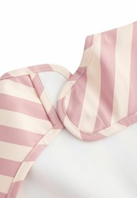 Pale pink and cream striped fabric with a ruffled neckline, featuring smooth texture and contrasting white background.