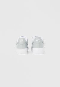 Para szarych i białych sneakersów Nike Air, widzianych od tyłu na jednolitym białym tle.