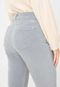 Pantaloni in cotone grigio misto con vita alta e cinque tasche, caratterizzati da una texture liscia e sottili dettagli di cucitura.