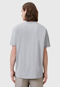 T-shirt grigio chiaro a maniche corte in tessuto morbido, con scollatura tonda e vestibilità comoda, caratterizzato da cuciture minime visibili.