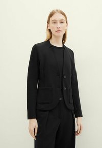 Blazer noir au design ajusté, avec deux poches avant et une fermeture à un bouton. Fabriqué en tissu texturé avec une finition lisse.
