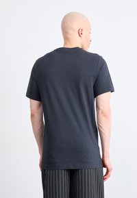 Tι να πω, τυπικό μπλουζάκι κοντομάνικο από βαμβάκι σε ναυτικό χρώμα με άνετη εφαρμογή. Ο πίσω πλευρά δείχνει λεία υφή και στρογγυλή λαιμόκοψη, συνδυασμένο με ριγέ παντελόνι.