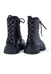 Stivali alla caviglia in pelle nera con occhielli dorati rotondi, soletta piatta, design con lacci e cerniera laterale. Tacco spesso con battistrada testurizzato.