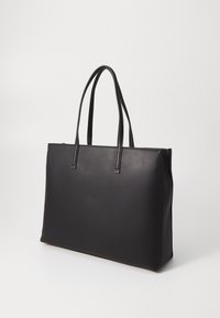 Sac cabas en cuir noir avec deux longues anses. Présente une texture lisse et une forme rectangulaire, adapté à un usage quotidien.