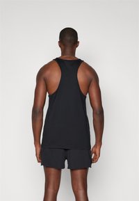 Top nero senza maniche con design racerback, realizzato in un tessuto liscio. Indossato con pantaloni corti neri, mostra una schiena muscolosa senza dettagli aggiuntivi.