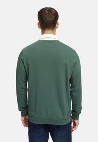 Groene pullovertrui gemaakt van zacht materiaal, met een witte kraag, lange mouwen en een relaxte pasvorm, met geribde manchetten en zoom.