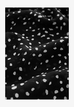 Črn material s teksturirano površino, okrašen s razpršenimi belimi in sivo neenakimi pikami, ki ustvarjajo sodoben tiskarski učinek.