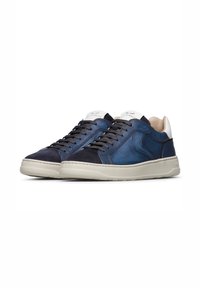 Un paio di sneakers in pelle blu navy a basso profilo con lacci neri e suole bianche, caratterizzate da punte in suede e colli del tallone bianchi.