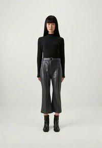 Must-haves muströid pikkade varrukatega must topp on kombineeritud kõrge vöökohaga hallide nahast lühikeste pükstega. Mudel kannab musti sääriseid. Lihtne disain koos voogava siluettiga.