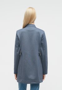 Sivý blejzer s priliehavým strihom, s výštuchovým golierom, dlhými rukávmi a hladkou textúrou, s dĺžkou do polovice stehien.