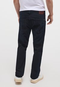 Jeans in denim blu scuro con una vestibilità dritta, dotati di due tasche posteriori, cuciture sottili e una patch in pelle con logo sulla vita.