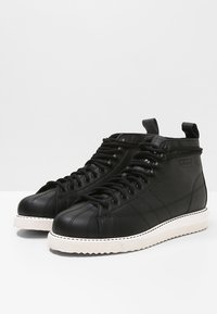Black leather high-top sneakers with a white rubber sole, featuring lace-up design and subtle stitched detailing.