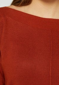 Pull en tricot couleur rouille avec un large décolleté bateau, présentant une texture subtilement côtelée et des coutures nettes.