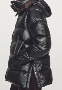 Giubbotto piumino nero con finitura lucida, dotato di cappuccio, tasche laterali e polsini a costine. Il design include sezioni trapuntate per l'isolamento.