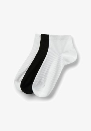 Drie geribbelde enkelsokken in wit, wit met een zwarte streep en effen zwart, overlappend gerangschikt op een witte achtergrond.