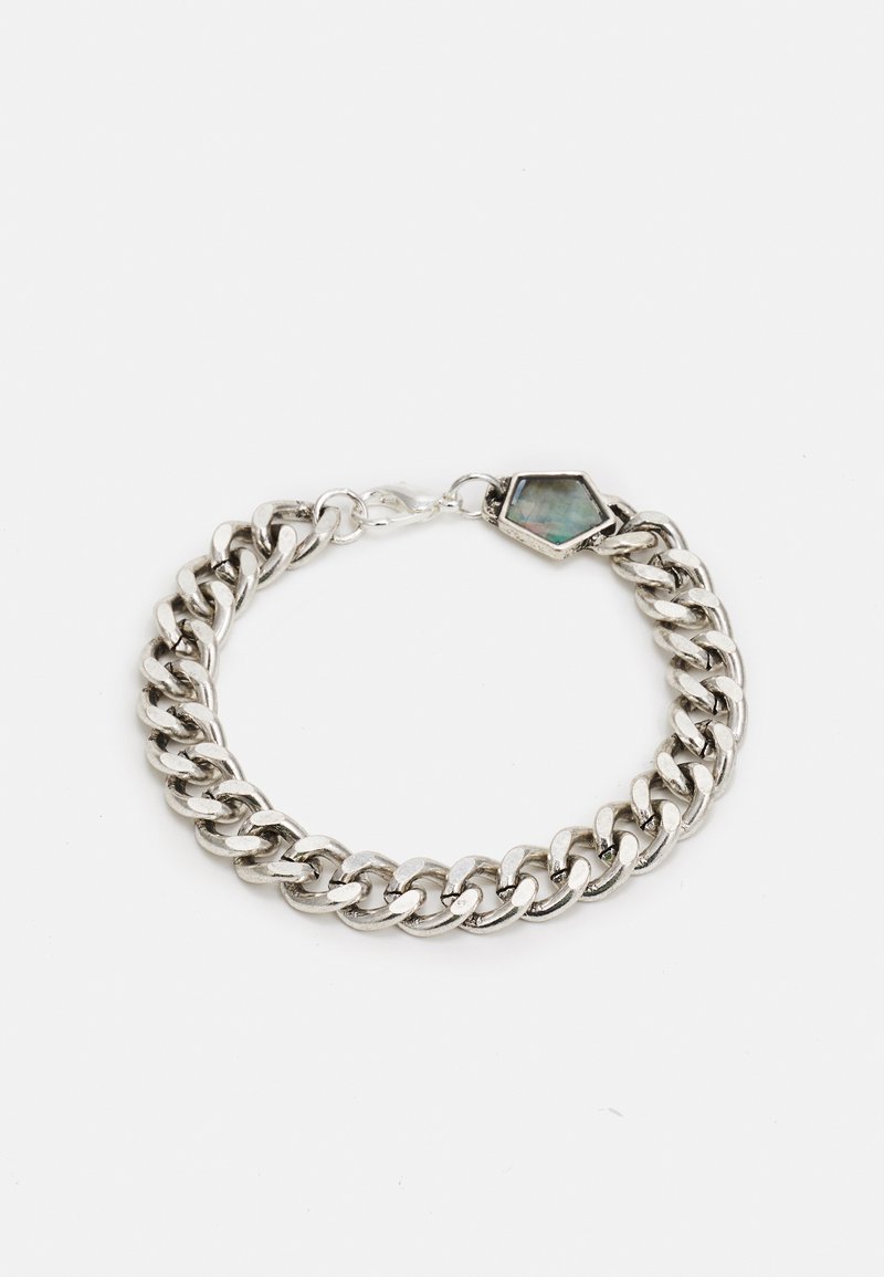 Pulseira de corrente prateada com elos entrelaçados e um acento de gema hexagonal. Textura suave com um acabamento polido. Ajusta-se com um fecho.