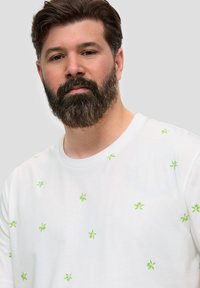 Witte katoenen T-shirt met verspreide groene bladerenpatronen, ronde hals, korte mouwen en een losse pasvorm.