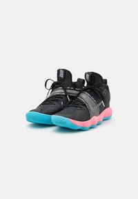 Zapatillas deportivas negras con suela rosa y turquesa, con parte superior de malla, talón reforzado y detalles impresos en las correas.
