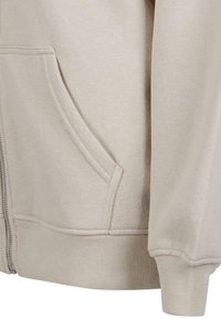 Beige zip-up hettegenser laget av mykt stoff, med sidelommer, ribbestrikkede mansjetter og nederkant, samt synlige sømdetaljer.