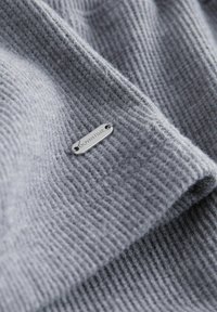 Mekanizam tkanine u mekom sivom vaflu s malom srebrnom oznakom na kojoj je ugravirana riječ "DOWNTIME."