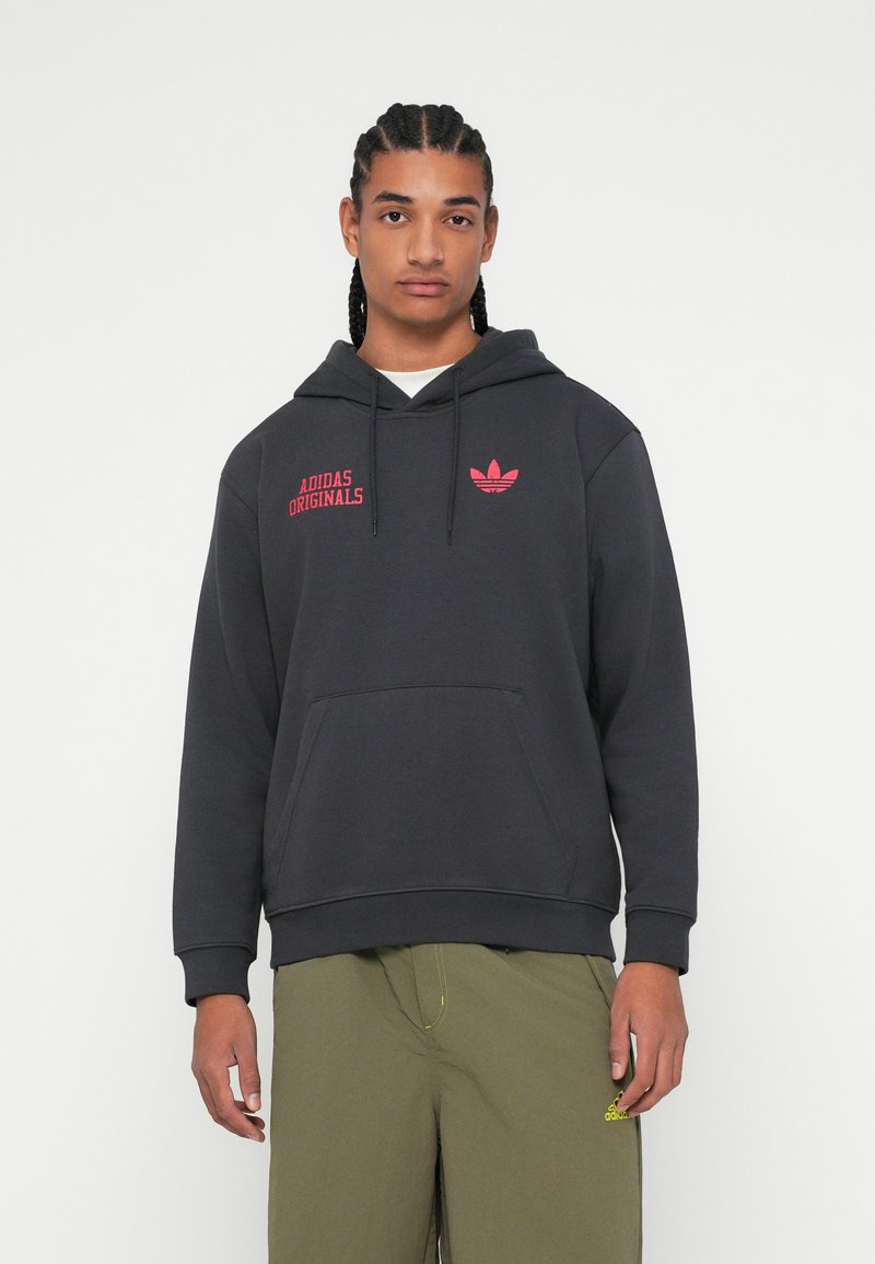 Čierna mikina s kapucňou so sladkým nápisom "ADIDAS ORIGINALS" a logom v červenej farbe. Obsahuje predn�é vrecko a kapucňu s šnúrkou. Hladká textúra, voľný strih.