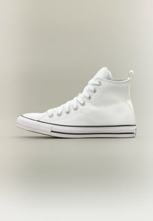 Λευκό καμβαδένιο αθλητικό παπούτσι τύπου high-top με λευκά κορδόνια, λαστιχένια σόλα, μαύρη ρίγα στη σόλα και θηλιά στο πίσω μέρος, πάνω σε απλό φόντο.