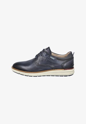 Zapato de cuero azul marino para hombres con diseño de cordones, acentos texturizados, detalles de costura y una suela de goma crema con un borde marrón.