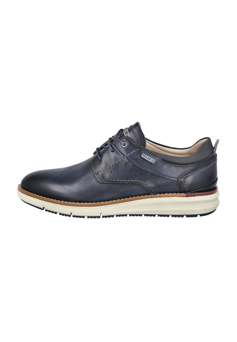 Zapato de cuero azul marino para hombres con diseño de cordones, acentos texturizados, detalles de costura y una suela de goma crema con un borde marrón.