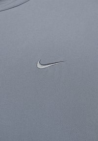 Lichtblauwe t-shirt van zachte stof, met een klein zwart geborduurd Nike-logo op de linkerkant van de borst.