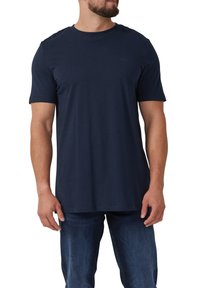 T-shirt blu navy a maniche corte con collo rotondo, realizzato in morbido cotone, con un logo sottile sul petto. Abbinato a jeans blu.