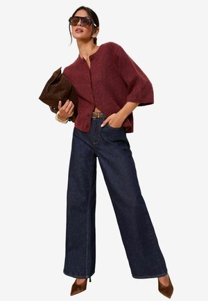 Maroon knit cardigan with a button front, paired with high-waisted dark denim wide-leg jeans and brown pointed-toe heels. Brown handbag.
