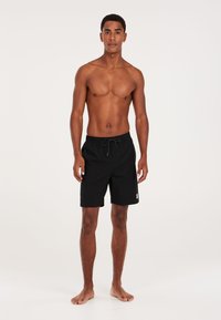 Zwarte zwemshorts met een elastische tailleband, koorddetail en een klein logo-embleem aan de zijkant. Lichtgewicht stof, knielange stijl.