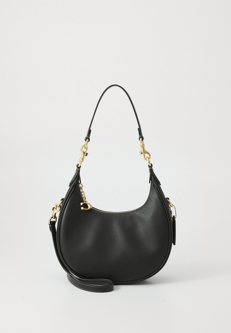 Μαύρη δερμάτινη τσάντα ώμου με καμπύλη μορφή, διαθέτει χρυσές λεπτομέρειες, αποσπώμενο λουρί και φερμουάρ κατά μήκος της επάνω πλευράς.