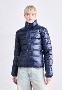Námorná puffer bunda s vysokým golierom, horizontálnym prešívaním, predným zipsom a elastickým pásom so štýlovým logom.