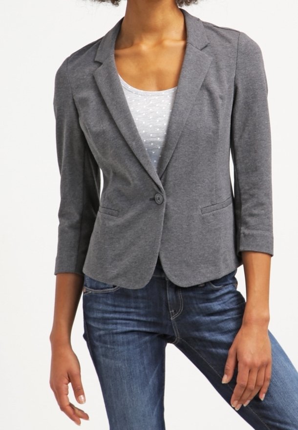 Blazer gris cintré en tissu doux avec une fermeture à un bouton, des revers crantés et deux poches latérales, porté sur un haut léger à motifs.
