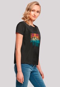 Black short-sleeve T-shirt featuring a colorful mountain and forest graphic design. Smooth texture, relaxed fit, crew neckline.
