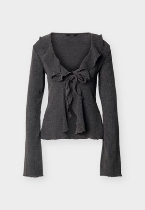 Σκούρα γκρι μακρυμάνικη μπλούζα με ριμπ ύφανση, γιακά με βολάν και λεπτομέρεια κορδονιού στο μπροστινό μέρος, εφαρμοστή σιλουέτα και ελαφρώς φαρδιά μανίκια.