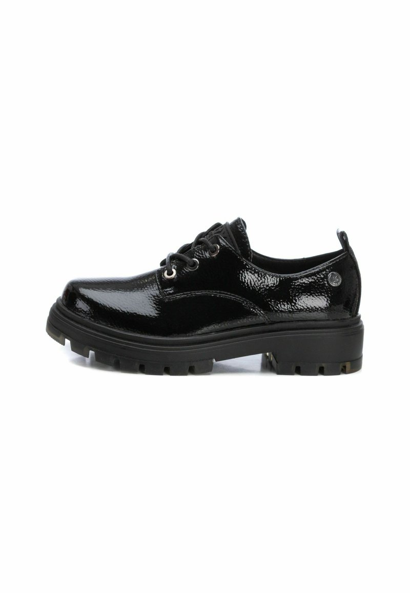 Zapatos de charol negro con punta redondeada, diseño de cordones y suela gruesa y robusta con patrones de relieve prominentes.