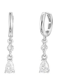 Les boucles d'oreilles en argent présentent une goutte de cristal en forme de poire et deux cristaux ronds au-dessus, suspendus à une surface lisse et polie.