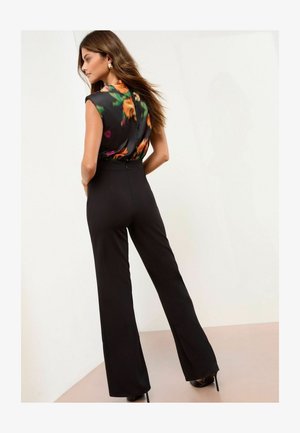 Juodi plačios kojų kelnės su prigludusia juosmeniu ir gėlėmis raštuotais šilko marškiniais. Lygi tekstūra, nugaros užtrauktukas ir trumpi rankovės.